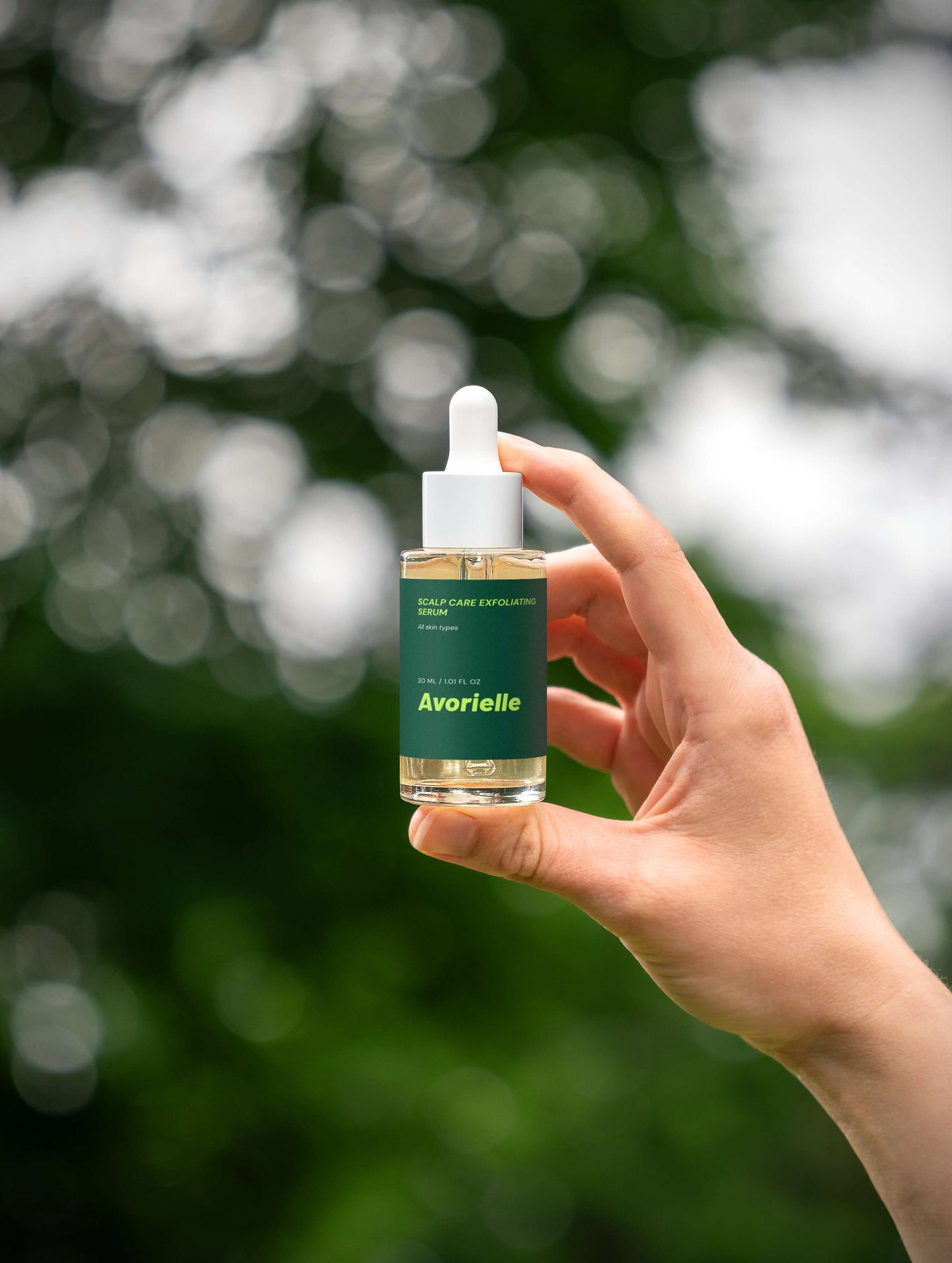 Scalp Care Exfoliating Serum in hand with blurred green background, promoting scalp exfoliating serum benefits for hair.